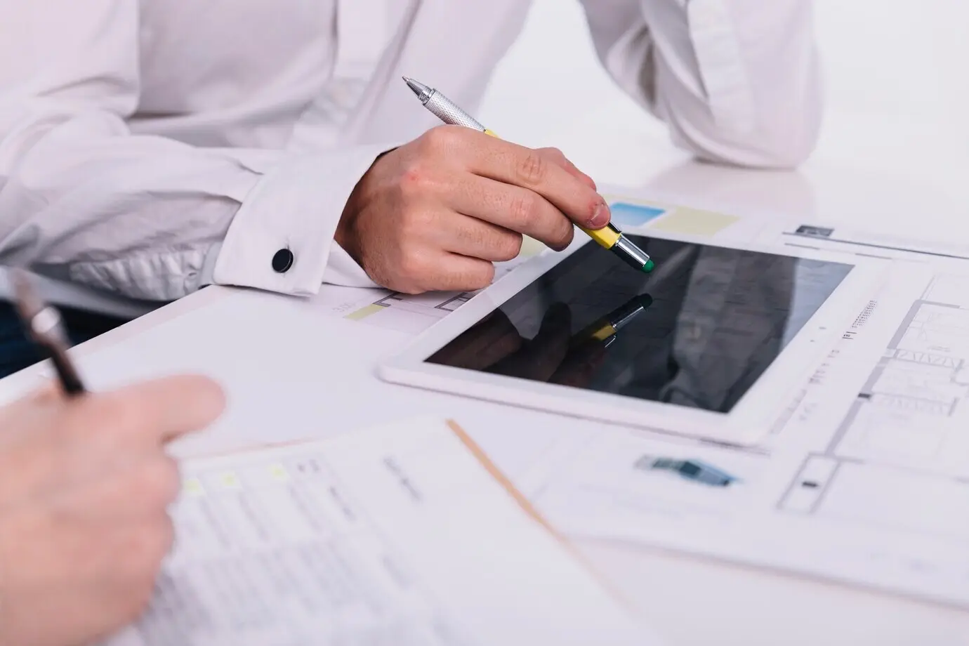 Zugeschnittene Aufnahme von Personen, die im Büro Entwürfe besprechen.