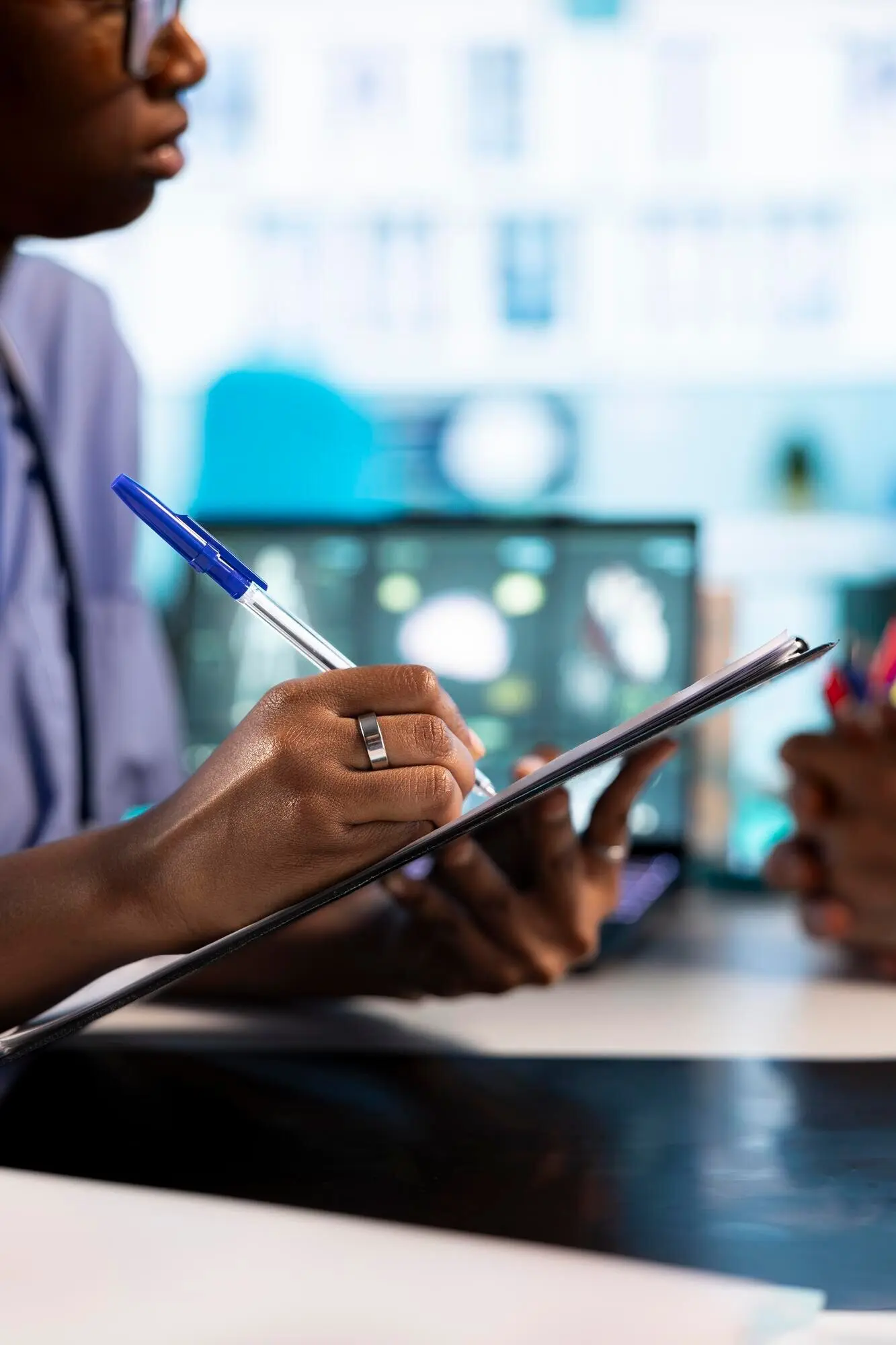 Afroamerikanische Pflegekraft macht sich Notizen während einer Beratung mit alten Menschen.